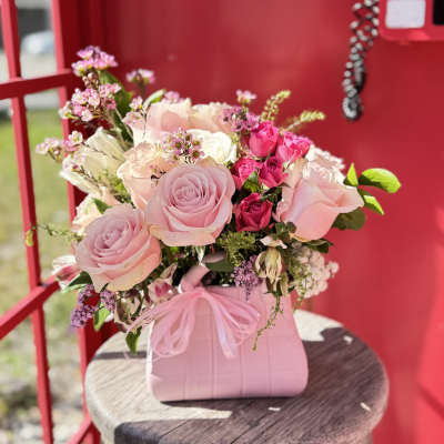Pink and white rose bouquet in a pink handbag-style container