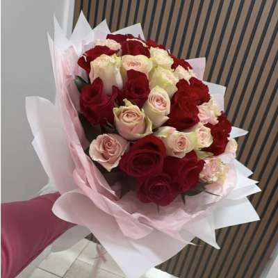 Bouquet of red and blush roses wrapped in pink paper