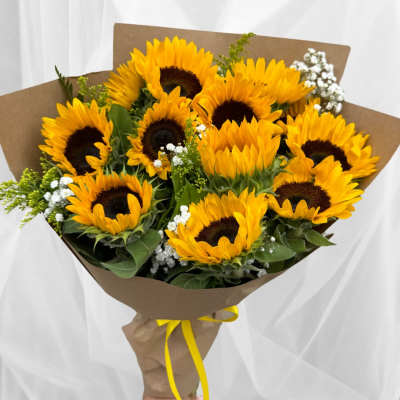 Bouquet of yellow sunflowers wrapped in brown paper with a yellow ribbon