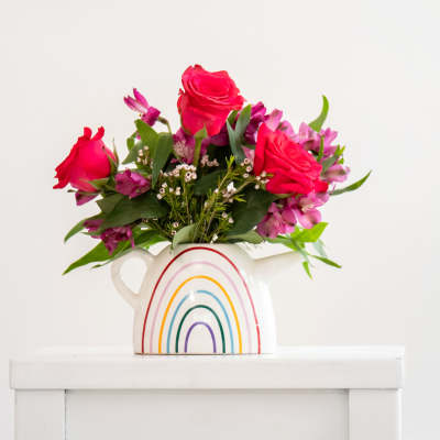 Pink roses and purple flowers in a rainbow pitcher vase