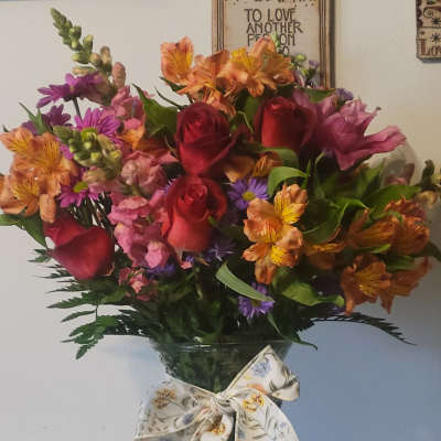 Mixed bouquet of roses, alstroemeria, and purple flowers in a glass vase