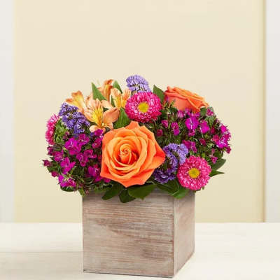 Orange roses and mixed purple-pink flowers in a wooden box