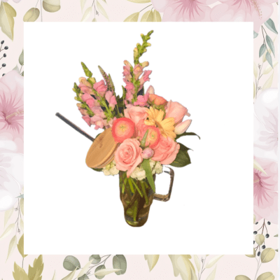 Pink and peach flowers arranged in a glass mug vase