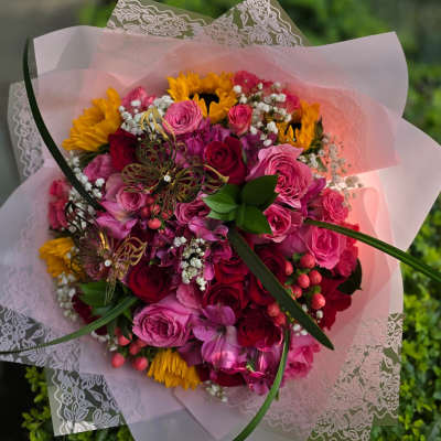 Bouquet of pink and red roses with yellow sunflowers in pink wrap
