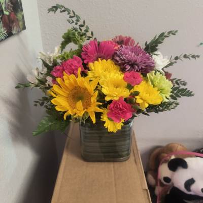Mixed bouquet of bright flowers in a square glass vase