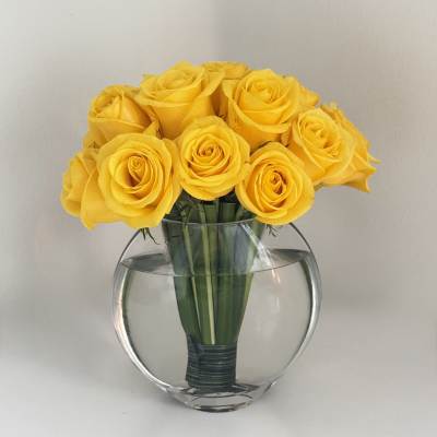 Yellow roses arranged in a clear round glass vase