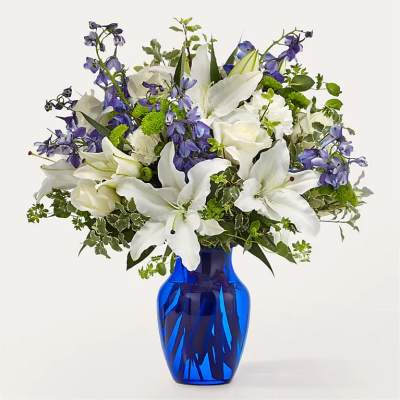 White lilies and blue flowers in a cobalt vase