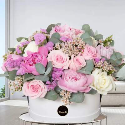 Pink and white roses and peonies arranged in a white hat box