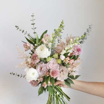 Handheld bouquet of pink and white flowers with long eucalyptus stems