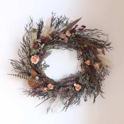 Decorative wreath with small pink roses and dried feathers