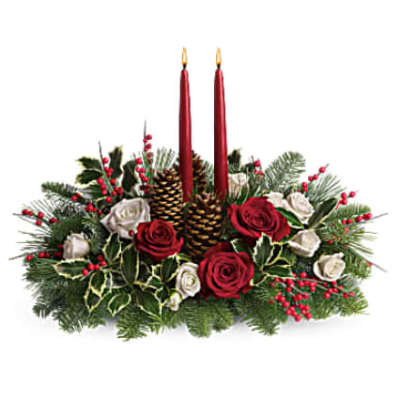 Low centerpiece of red and white roses with pine, holly, pinecones and two red taper candles