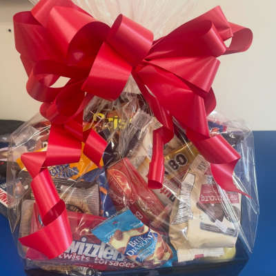 Gift basket of assorted snacks wrapped in clear cellophane with a large red bow