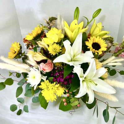 Mixed bouquet with white lilies, yellow sunflowers, and a pink rose