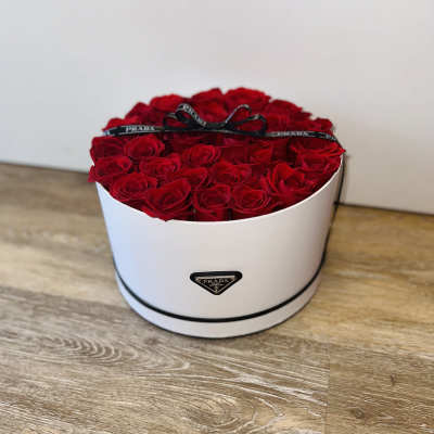Round box filled with red roses and a black ribbon