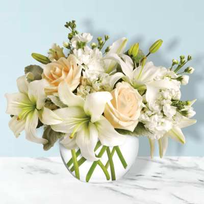 White lilies and peach roses in a clear glass vase