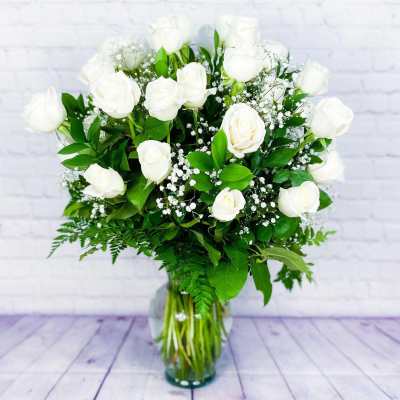 White rose bouquet in a clear glass vase with baby's breath