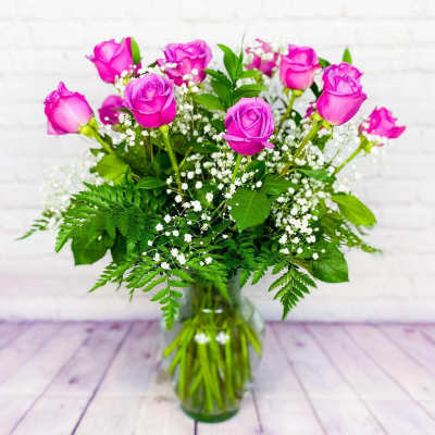 Pink roses arranged in a clear glass vase with white filler flowers