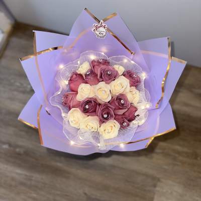 Bouquet of pink and cream roses wrapped in lavender paper