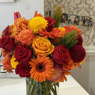 Bright mixed bouquet of roses, gerbera daisies, and chrysanthemums in a glass vase