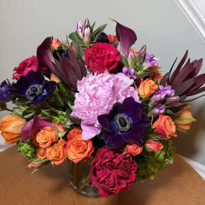Mixed bouquet of pink, orange, and purple flowers in a glass vase