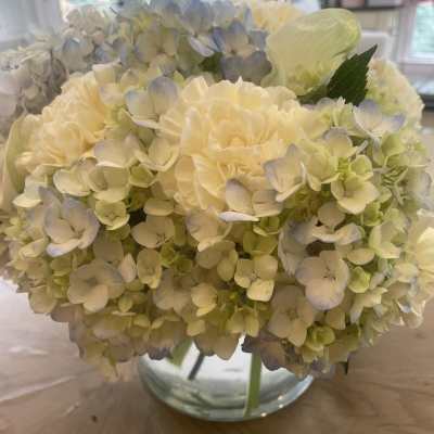 Cream and pale blue hydrangea bouquet in a clear glass vase