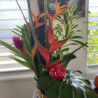 Tropical flower arrangement with orange and red heliconia in a vase