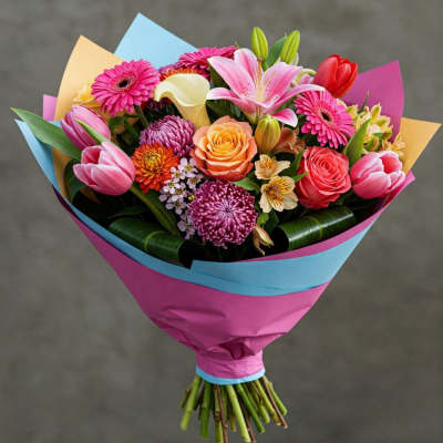 Bouquet of pink, peach, and white flowers wrapped in bright paper