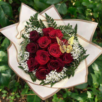 Bouquet of red roses with white filler flowers and a butterfly decoration