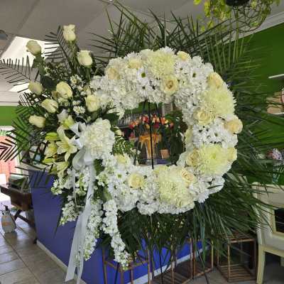 Large white floral wreath on a stand with ribbon bows