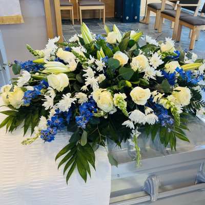 Large white and blue floral casket spray with roses and lilies