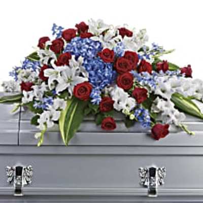 Red roses, white lilies, and blue flowers arranged on a silver casket