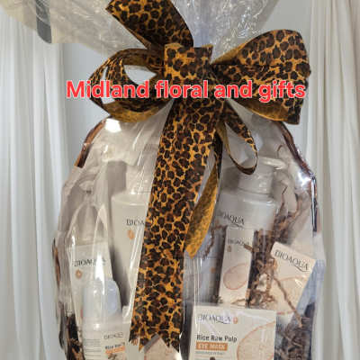 Gift basket with skincare products wrapped in clear cellophane and a leopard-print bow