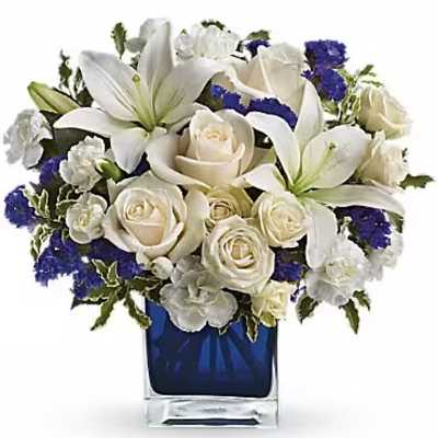 White lilies and roses arranged in a blue glass vase