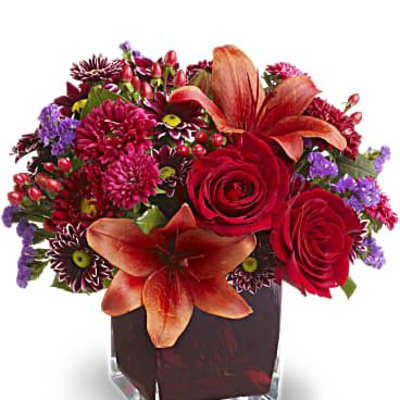 Red roses and orange lilies in a square glass vase