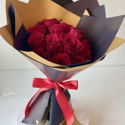 Bouquet of red roses wrapped in gold and dark paper with a red ribbon