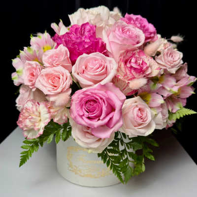 Pink and white roses arranged in a white hat box