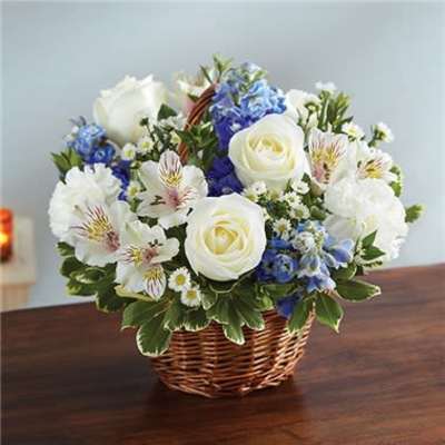 Basket arrangement of white roses and blue flowers