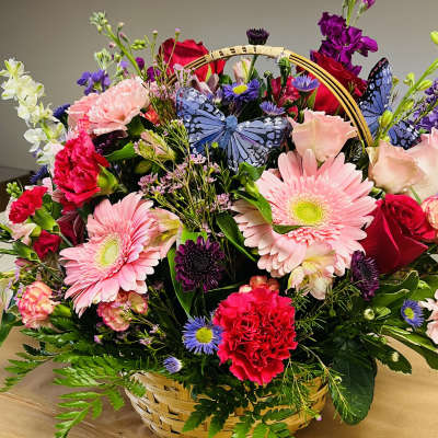 Mixed flower basket with pink gerberas, roses, carnations, and butterflies