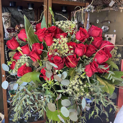 Large bouquet of red roses in a glass vase with greenery