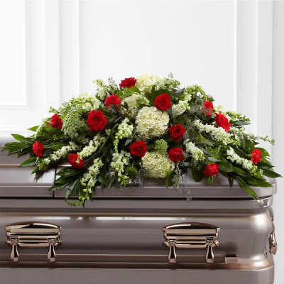 Red roses and white flowers arranged on a silver casket