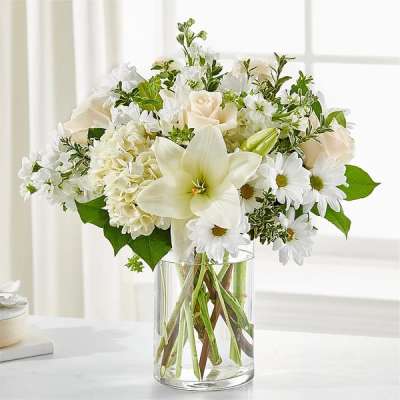 White flowers arranged in a clear glass vase with green accents