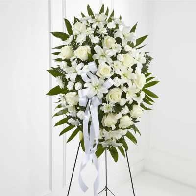 White floral standing spray with a ribbon on a black easel