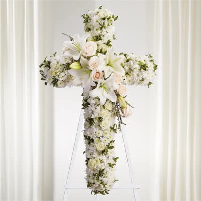 White floral cross arrangement with roses and lilies on a stand
