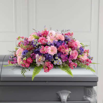 Pink and purple floral spray arranged on a casket