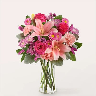 Pink lilies, roses, and carnations in a clear glass vase