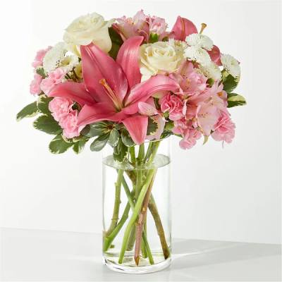 Pink lilies, roses, and carnations in a clear glass vase