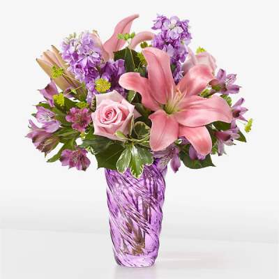 Pink lilies and purple flowers in a purple glass vase
