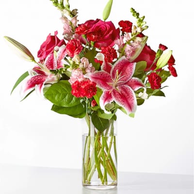 Pink lilies, roses, and carnations in a clear glass vase