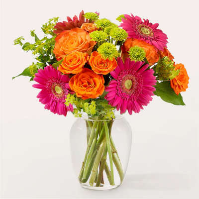 Bouquet of orange roses and pink gerbera daisies in a clear glass vase