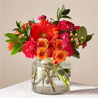 Orange and pink mixed bouquet in a clear glass vase
